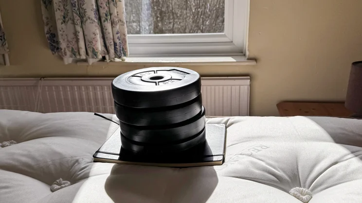 A notebook and series of weights placed on the surface of the Sleepeezee Regency Kennington 4200 mattress, measuring sinkage