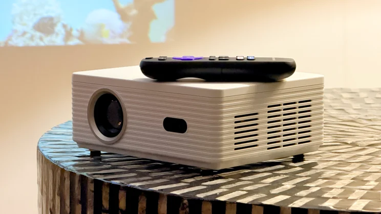 The Sharp Roku TV Smart Projector with remote control pictured from the front on a coffee table