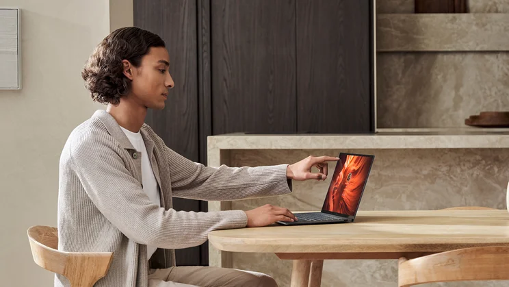 Man using Asus Zenbook laptop touchscreen, sat at table