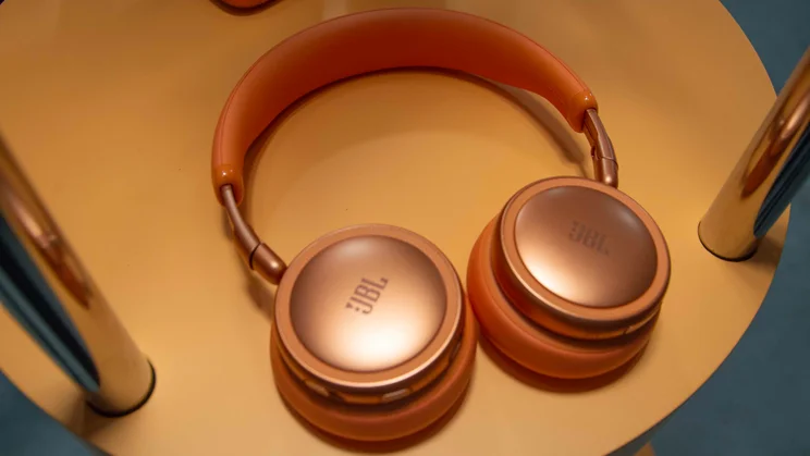 The JBL Live 680NC on-ear headphones in orange on an orange plinth