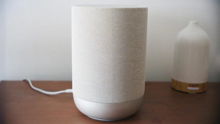 Side view of the Denon Home 400 wireless speaker alongside a scent diffuser on a wooden table