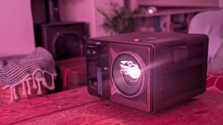 The Hisense XR10 laser projector on a wooden table projecting in a dark room