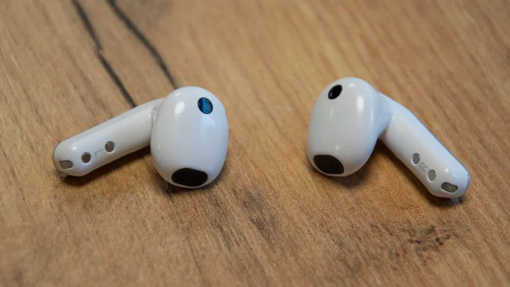 The Samsung Galaxy Buds4 on a wooden table with the earbud housings facing inwards
