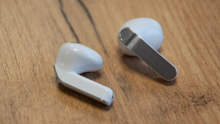 The Samsung Galaxy Buds4 on a wooden table side-by-side
