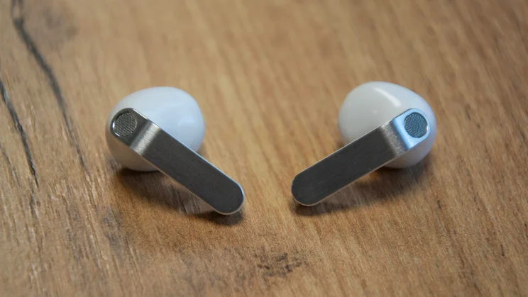The Samsung Galaxy Buds4 on a wooden table with their stems facing inwards