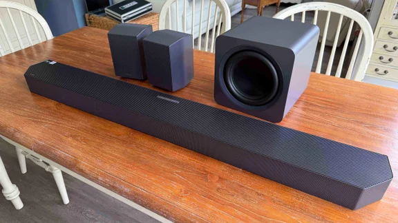 The Samsung HW-Q990H soundbar, subwoofer and rear speakers on a wooden table