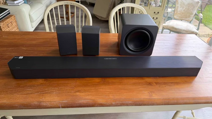 Front view of the Samsung HW-Q990H soundbar, subwoofer and rear speakers on a wooden table