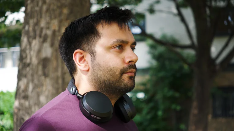 The Sennheiser Momentum 5 Wireless over-ear headphones being worn around the neck of our reviewer
