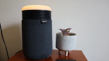 The Blueair Mini Restful air purifier on a bedside table, alongside a small potted plant