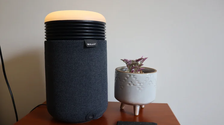 The Blueair Mini Restful air purifier on a bedside table, alongside a small potted plant