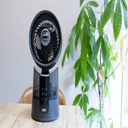 The Dreo TurboCool Misting Fan 516S on a table in an office, in front of a large potted plant