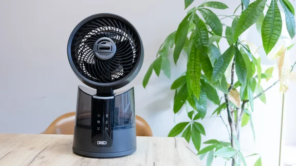 The Dreo TurboCool Misting Fan 516S on a table in an office, in front of a large potted plant