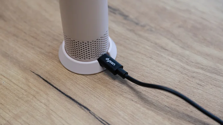 A closeup of the Dyson HushJet Mini Cool fan's base, with charging cable plugged in