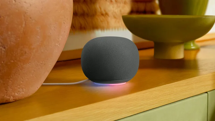 The Google Home Speaker with its light ring glowing, on a shelf
