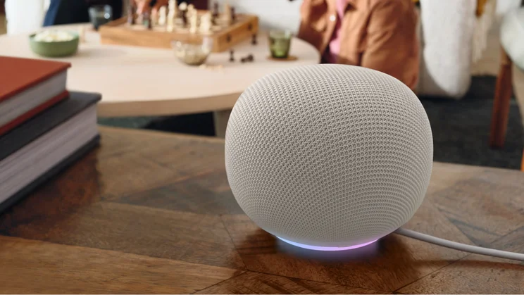The Google Home Speaker, in the porcelain colourwauy, pictured on a coffee table