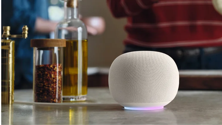 The Google Home Speaker, in porcelain, pictured on a kitchen table with an olive oil and crushed chillies in a jar next to it on the left