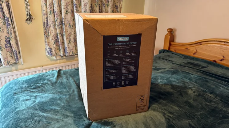 The Simba Cool Foam mattress topper in its box, on top of a mattress