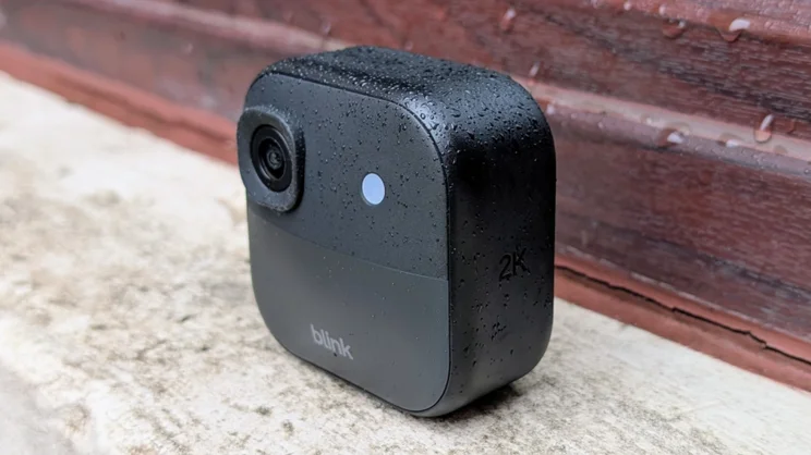 The Blink Outdoor 2K+ camera pictured on a window ledge from the front right quarter