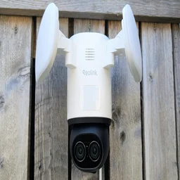 The Reolink TrackFlex, pictured from in front, mounted on a wooden fence