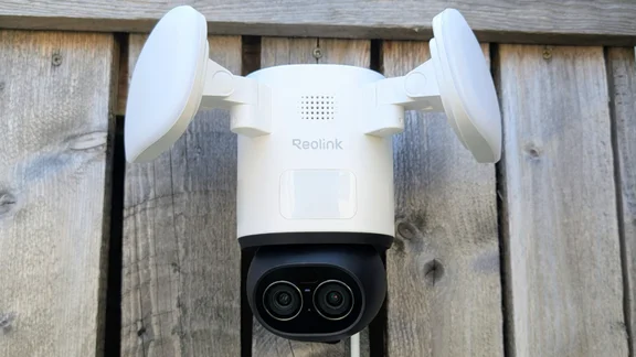 The Reolink TrackFlex, pictured from in front, mounted on a wooden fence