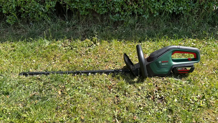 Bosch AdvancedHedgeCut 36V - wide shot of trimmer laid on grass