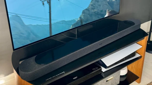 The Bose Lifestyle Ultra Soundbar on a TV stand in front of television