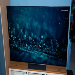 The 65in LG C6 OLED TV on a wooden stand displaying an image of raindrops falling