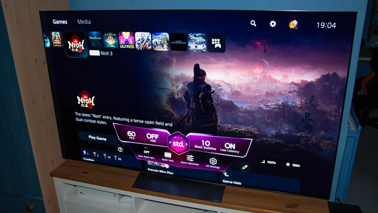 The 65in LG C6 OLED TV on a wooden stand displaying the Game Dashboard on the PlayStation 5 homepage