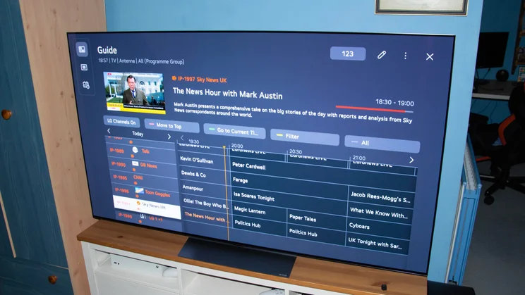 The 65in LG C6 OLED TV on a wooden stand displaying the LG Channels TV guide