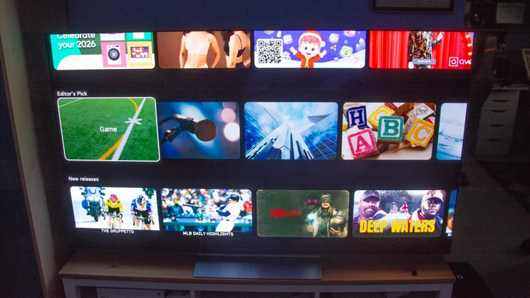 The 65in LG C6 OLED TV on a wooden stand displaying several rows of content on webOS 26