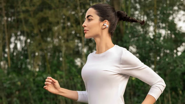 Lifestyle shot of a woman running while wearing the Shokz OpenDots 2