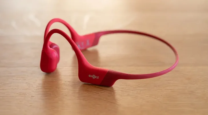 The Shokz OpenRun bone-conduction headphones on a wooden surface