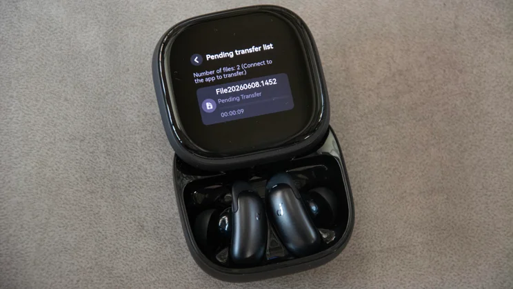 The Soundcore Liberty 5 Pro Max wireless earbuds in their charging case with the lid open transferring a file to the Soundcore app