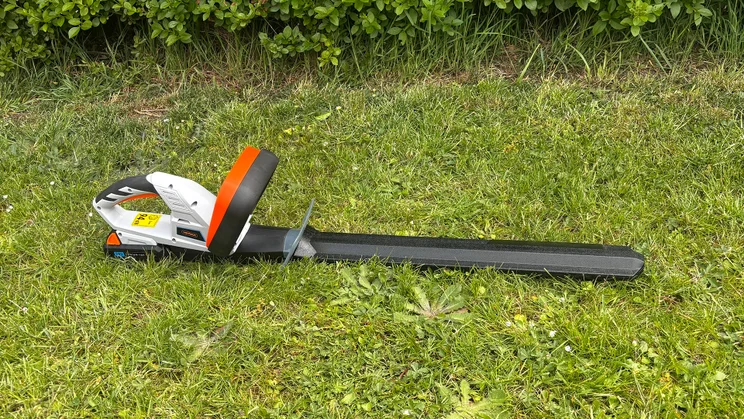 Wide shot of the VonHaus G-Series 40V hedge trimmer, lying on grass sheathed