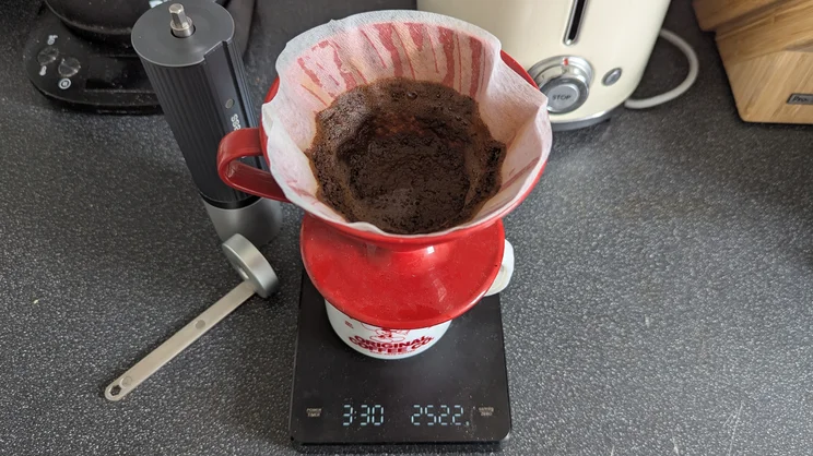 A bird's eye view of a Hario V60 brewer, with a bed of leftover coffee grounds in it