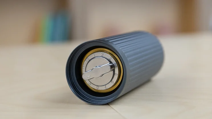The AeroPress Manual Coffee Grinder lying on its side, showing the grind adjustment dial on the base