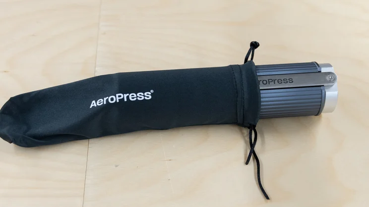 The AeroPress Manual Coffee Grinder partially in its travel pouch