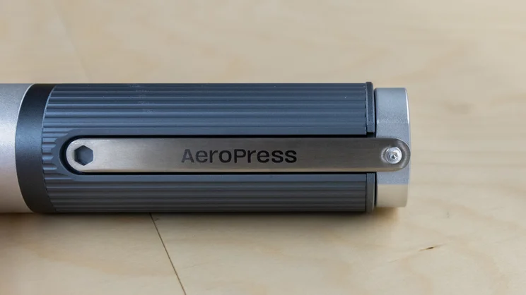 A partial view of the AeroPress Manual Coffee Grinder, with its handle stored, lying on its side