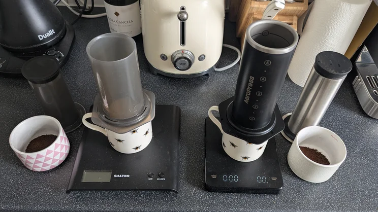 A bird's eye view of the AeroPress Steel coffee maker alongside the AeroPress Original, both being used to make coffee side by side