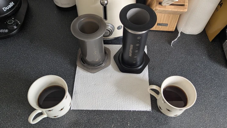 A bird's eye view of the AeroPress Steel coffee maker alongside the AeroPress Original, both being used to make coffee side by side