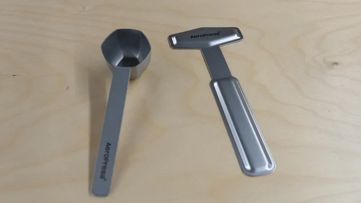 The AeroPress Steel coffee maker's accessories: a stirring paddle and a coffee scoop