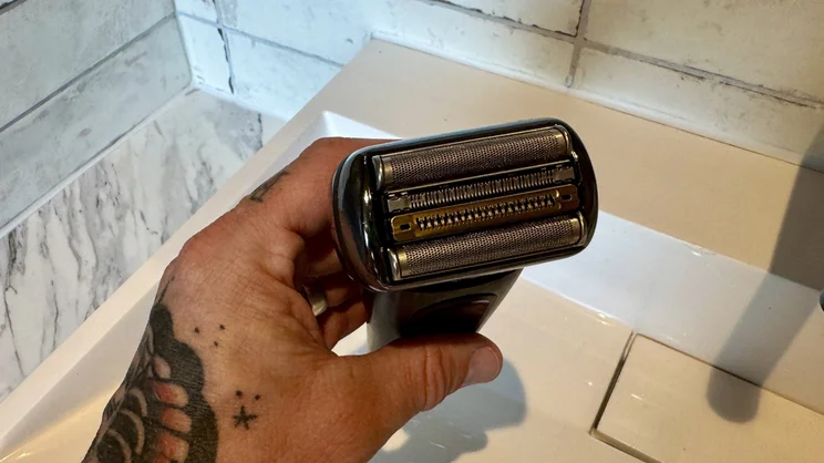 A view of the Braun Nevo electric shaver's foil head, in a hand over a bathroom sink