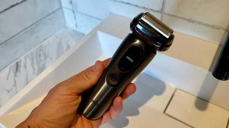 The Braun Nevo electric shaver in a hand, held over a sink