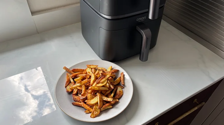 A plate of cooked chips on a kitchen worktop, alongside the Cosori Turbo Tower air fryer