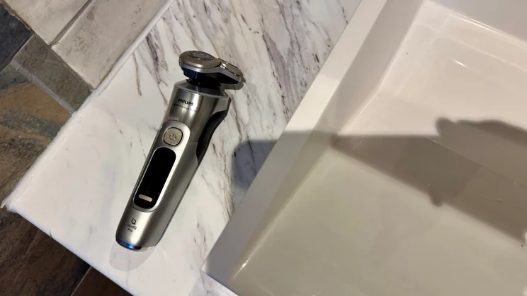 Philips i9000 Prestige Ultra - wide shot of shaver lying on sink edge