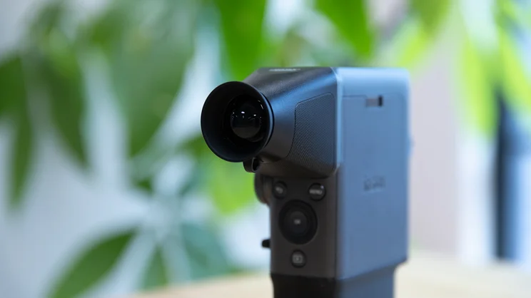 A closeup of the Instax Mini Evo Cinema, with viewfinder attachment, on a table in an office
