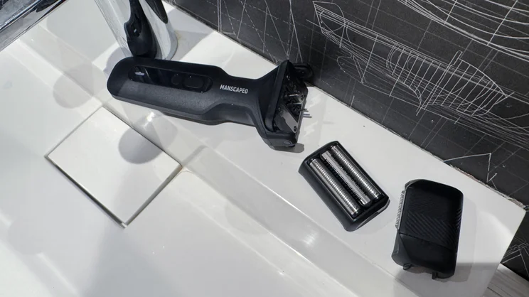 The Manscaped Chairman Plus electric shaver, with both heads removed, on the side of a sink