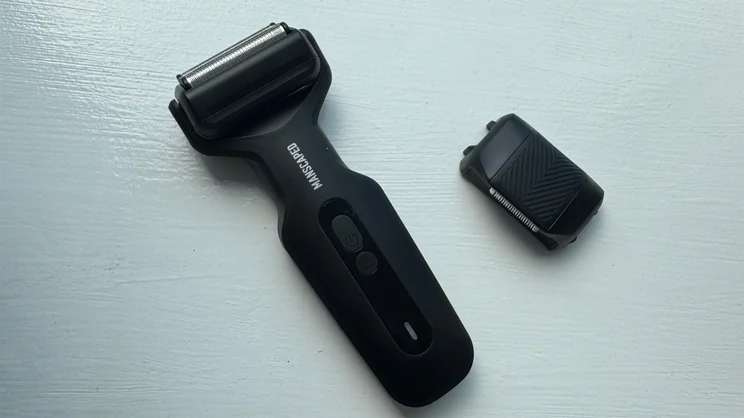 A bird's eye view of the Manscaped Chairman Plus electric shaver, with foil head attached, alongside its precision tool head