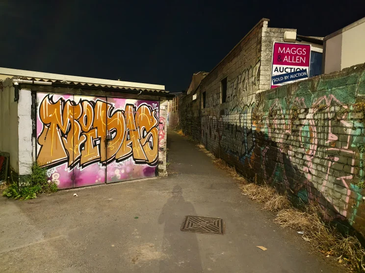 A graffiti-covered alleyway at night