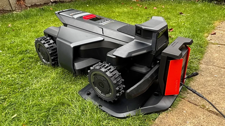 The Segway Navimow X430 robot lawnmower docked on its base, in a garden